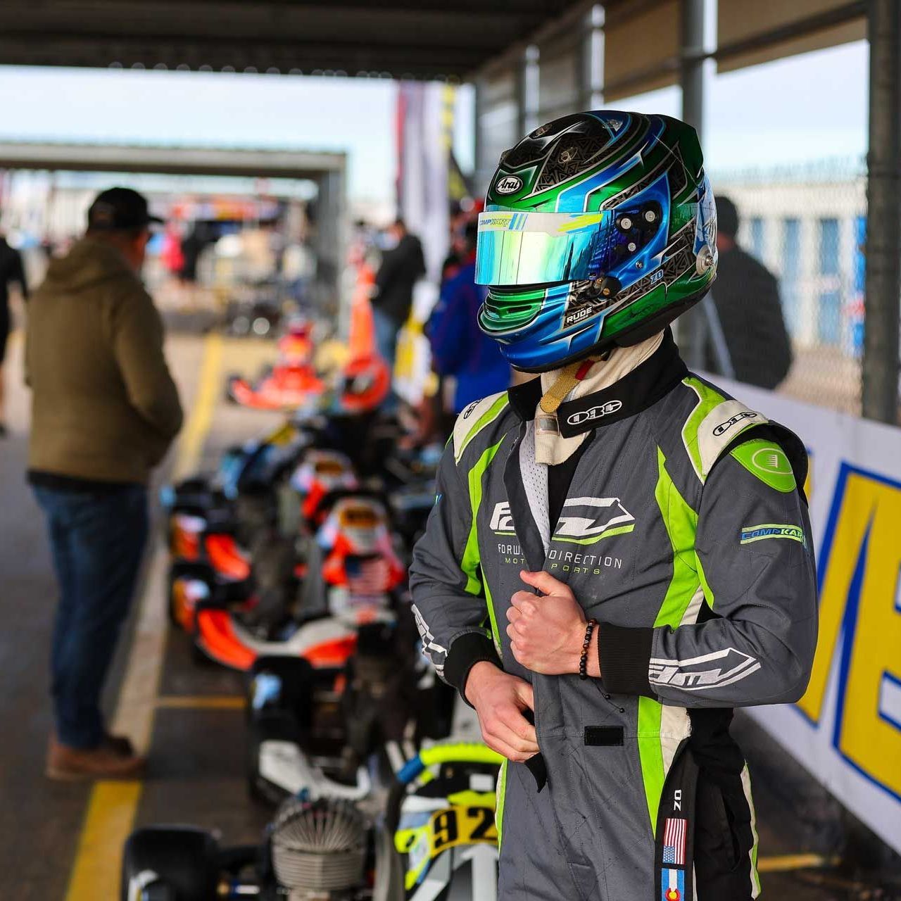 A man wearing a helmet sits on a go kart with the number 36 on it