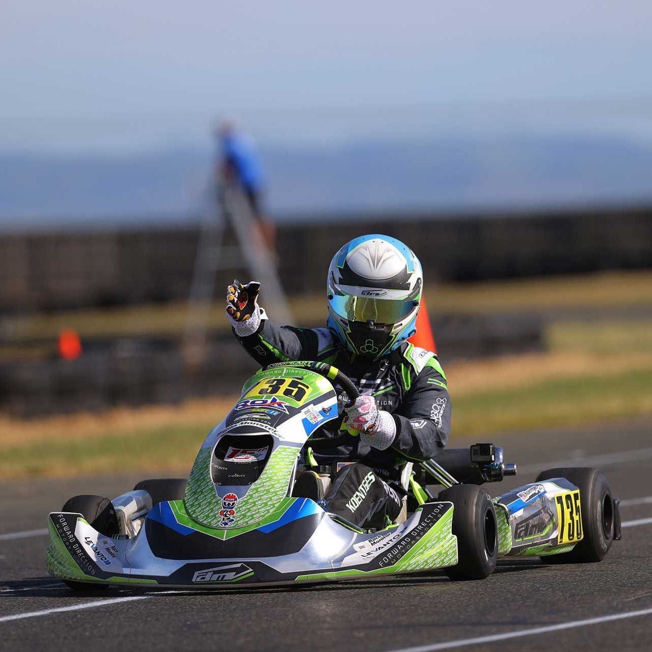 A man wearing a helmet sits on a go kart with the number 36 on it