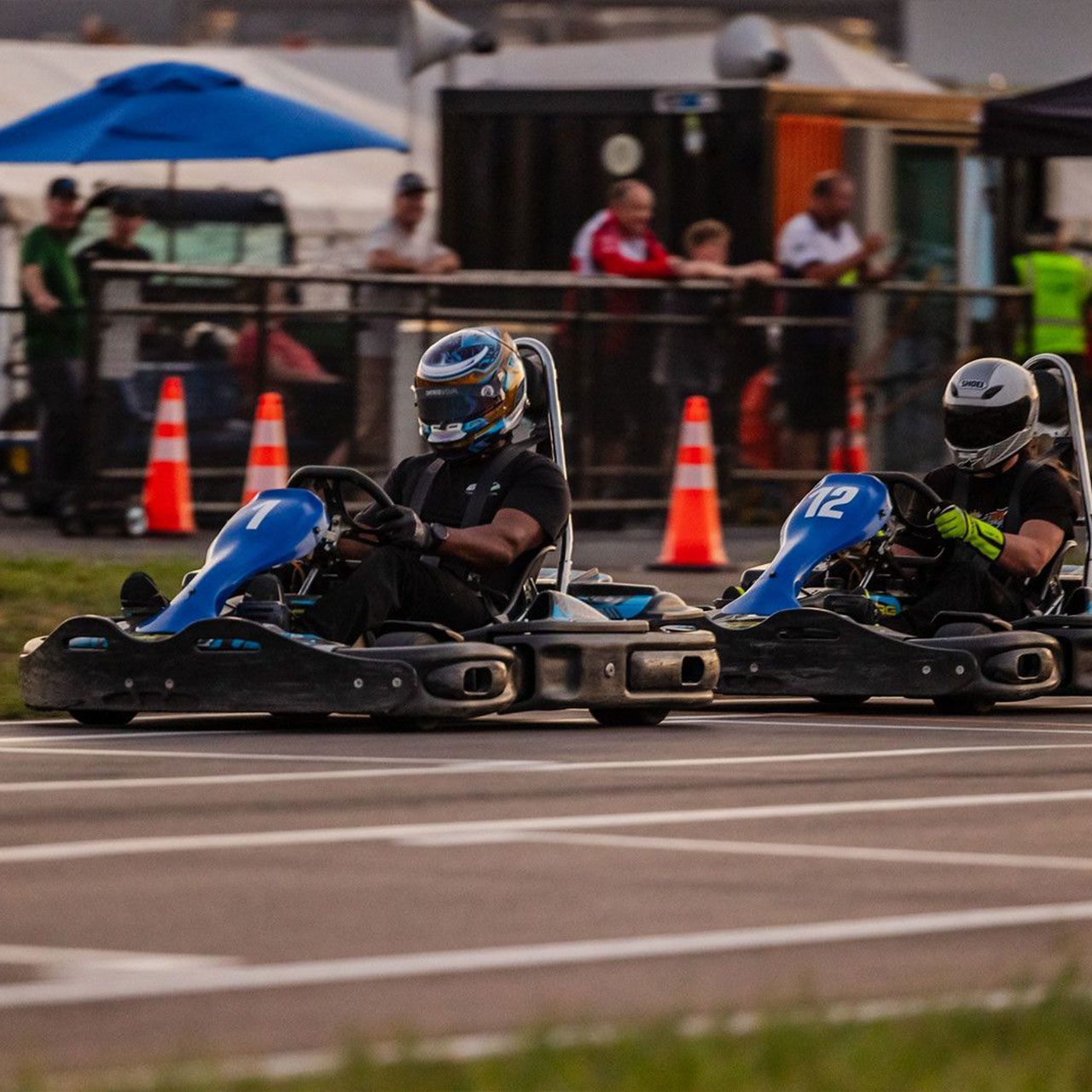 Two people are riding go karts on a track.