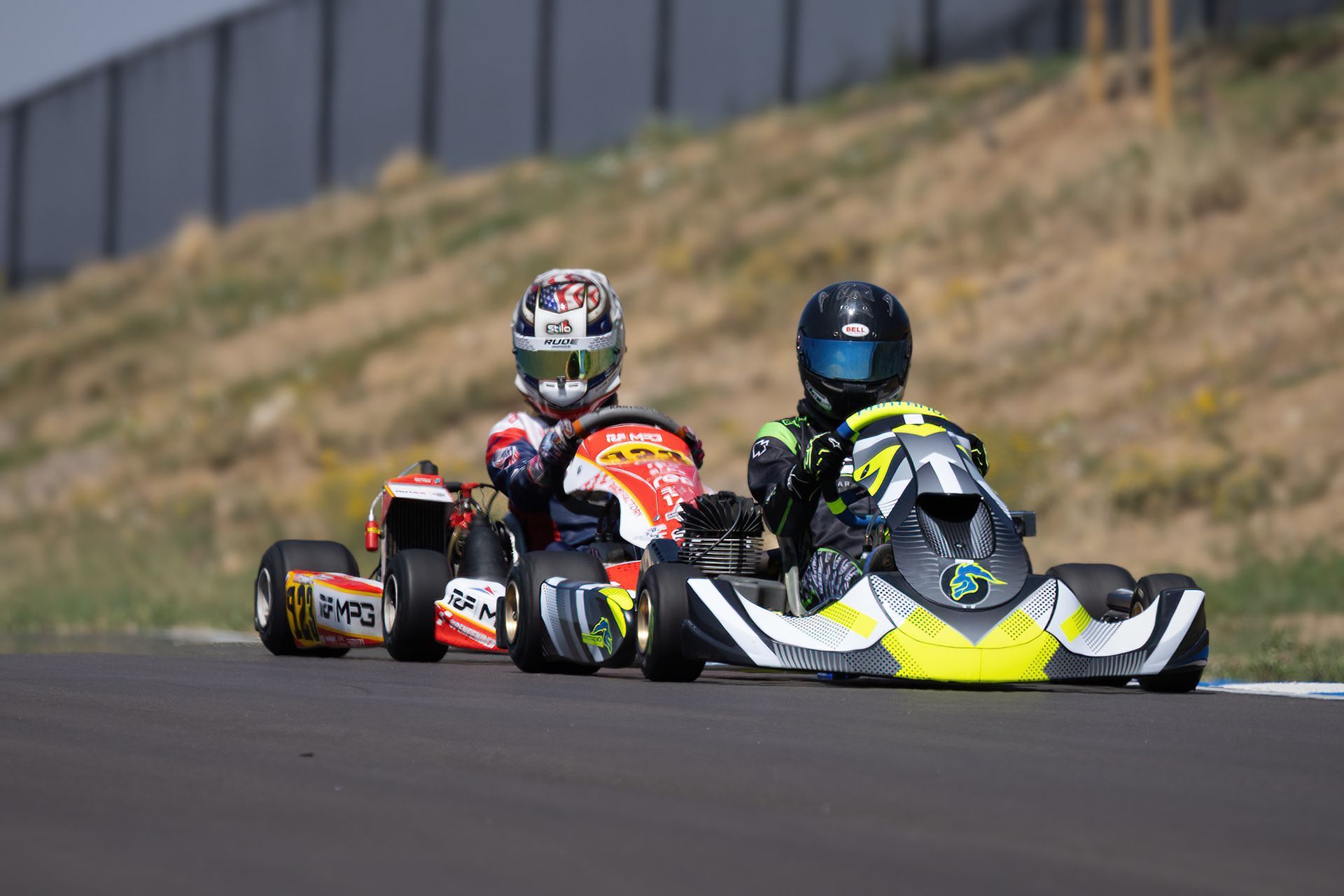 Two people are racing go karts on a track.