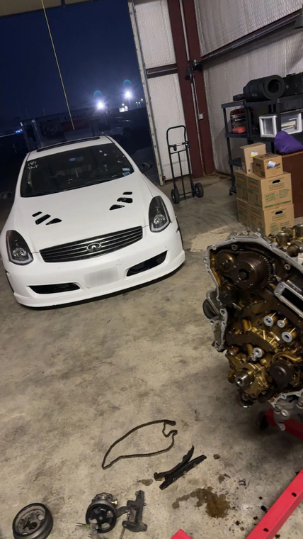 White sports car in a garage with tools and car parts scattered on the floor
