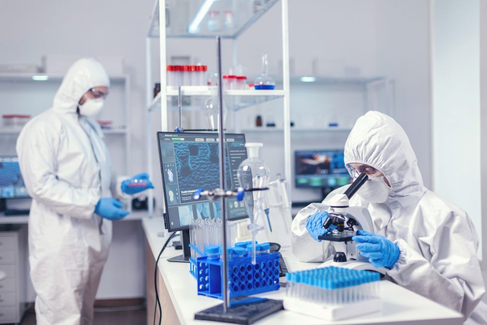 Two scientists in protective suits are working in a laboratory.