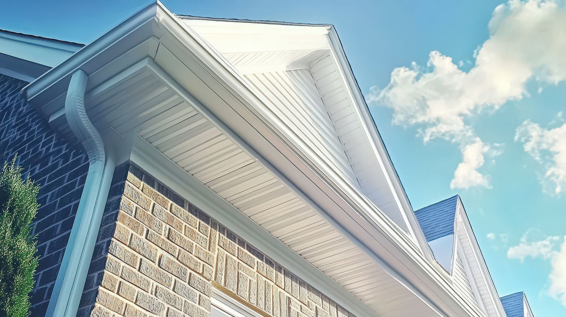 A brick house with a white roof and gutters