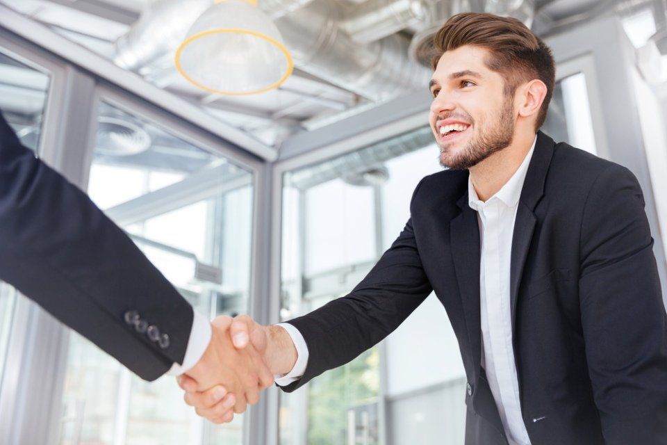 Un uomo in giacca e cravatta stringe la mano a un altro uomo in un ufficio.