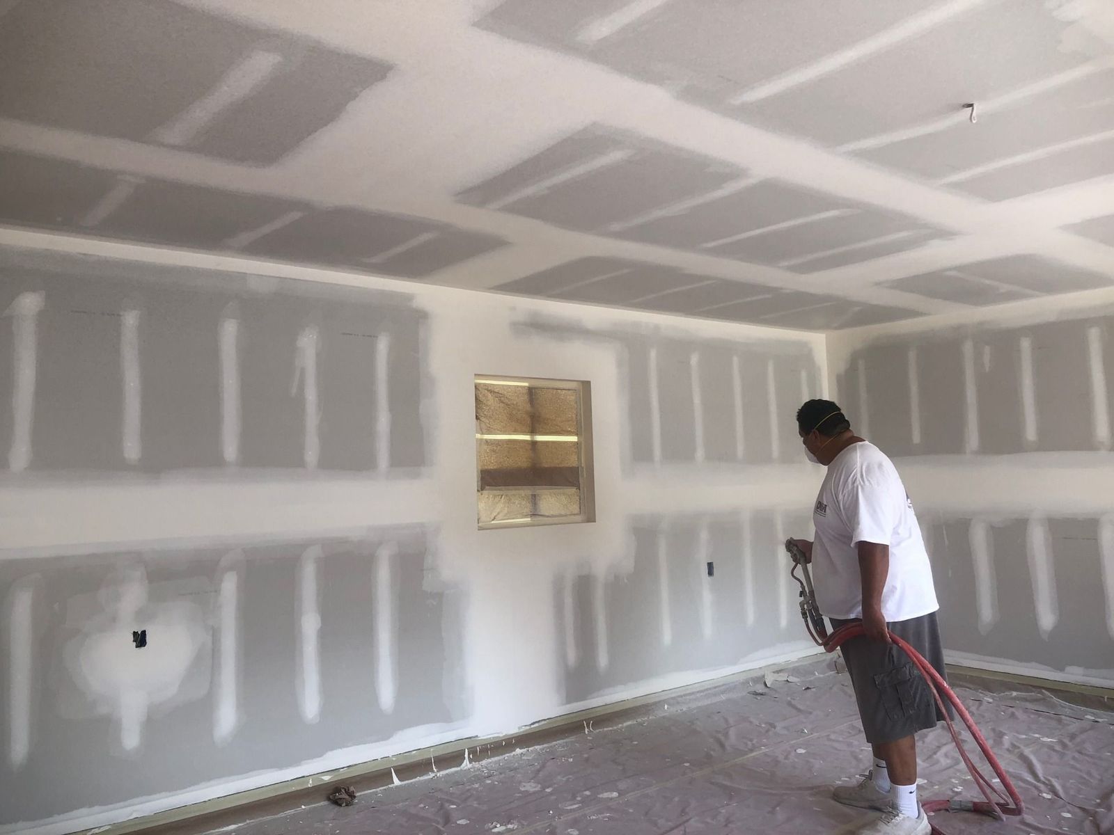A man is spraying a room with a hose.