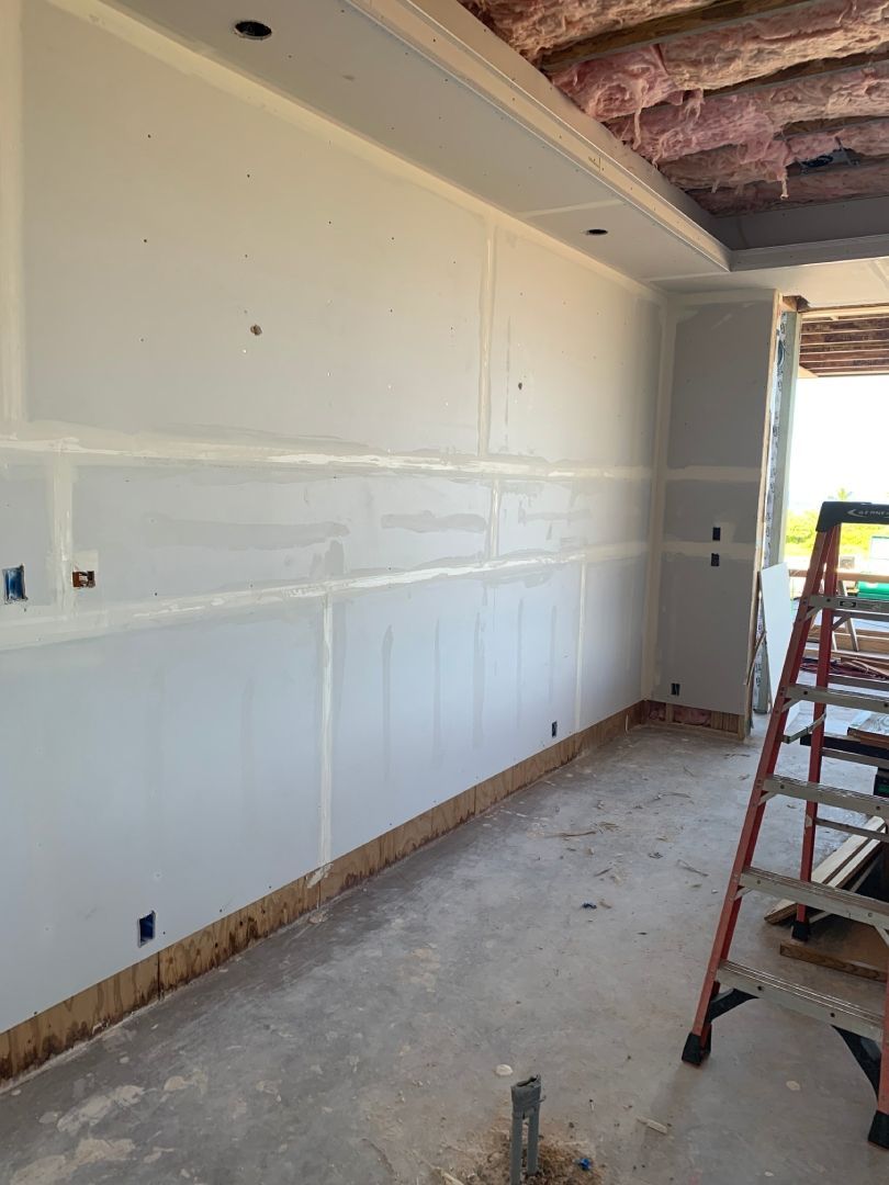 There is a ladder in the middle of the room with drywall installed.