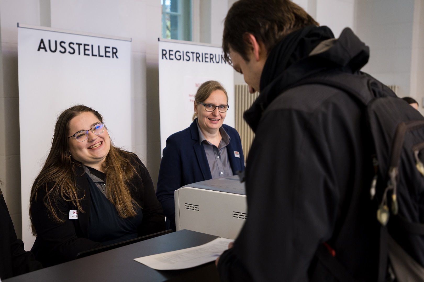 Team von KUKM an der Registrierung des neuroRAD 2022 im Gespräch mit Teilnehmer