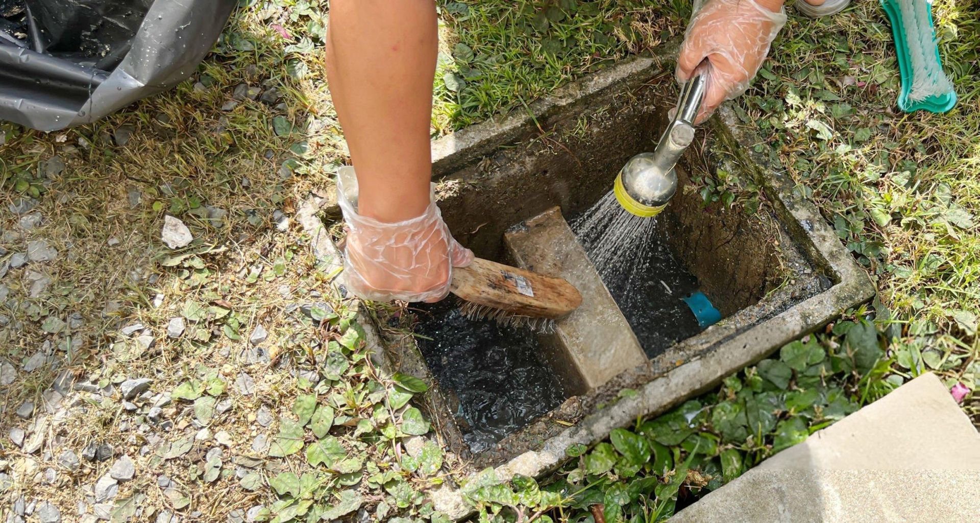 An unrecognized person is providing commercial grease trap cleaning services with a wire brush.