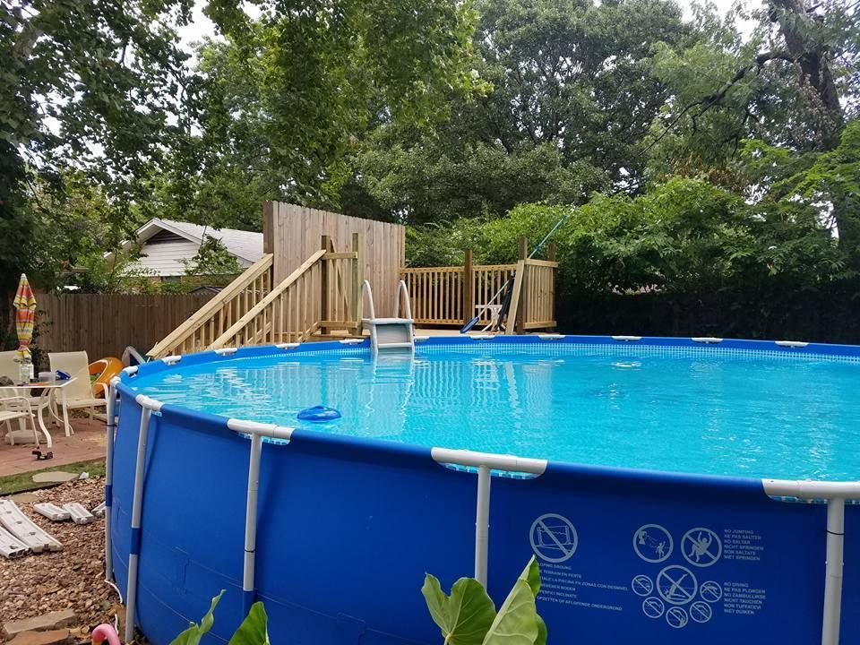 Above-ground pool in a backyard with a wooden deck and trees surrounding it