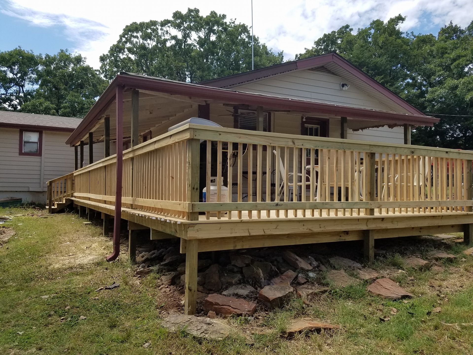 Small house with a newly built wooden front porch and ramp, viewed from the yard.