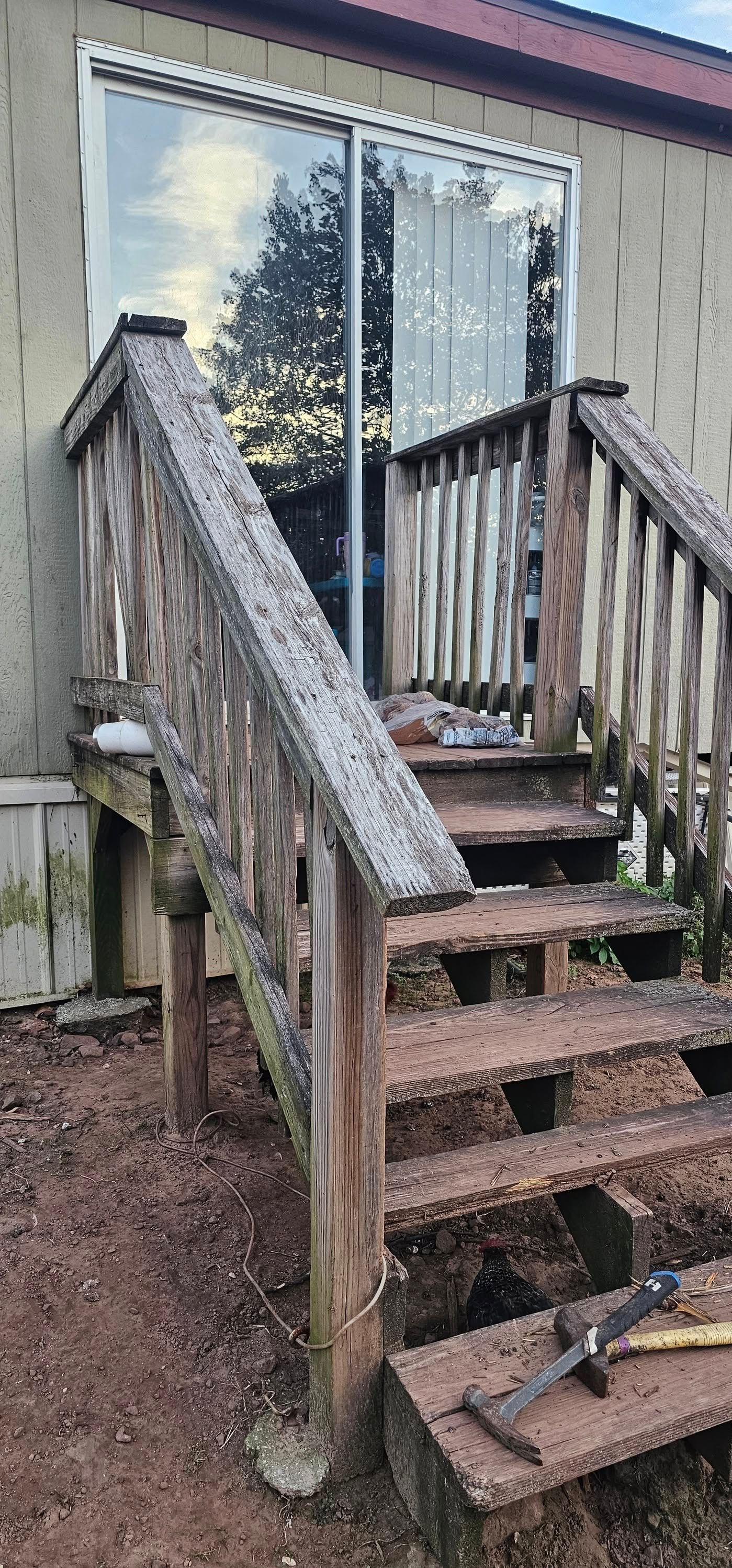 Weathered wooden porch stairs leading to a glass door on a house exterior