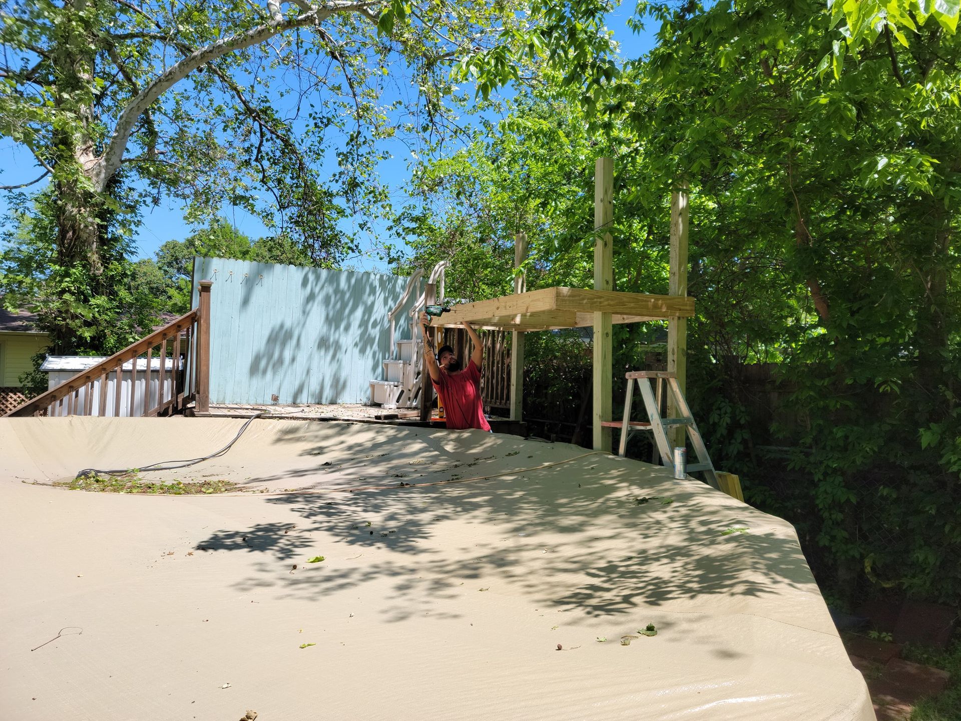Sandy slope leading to a small shed and wooden deck under trees on a sunny day