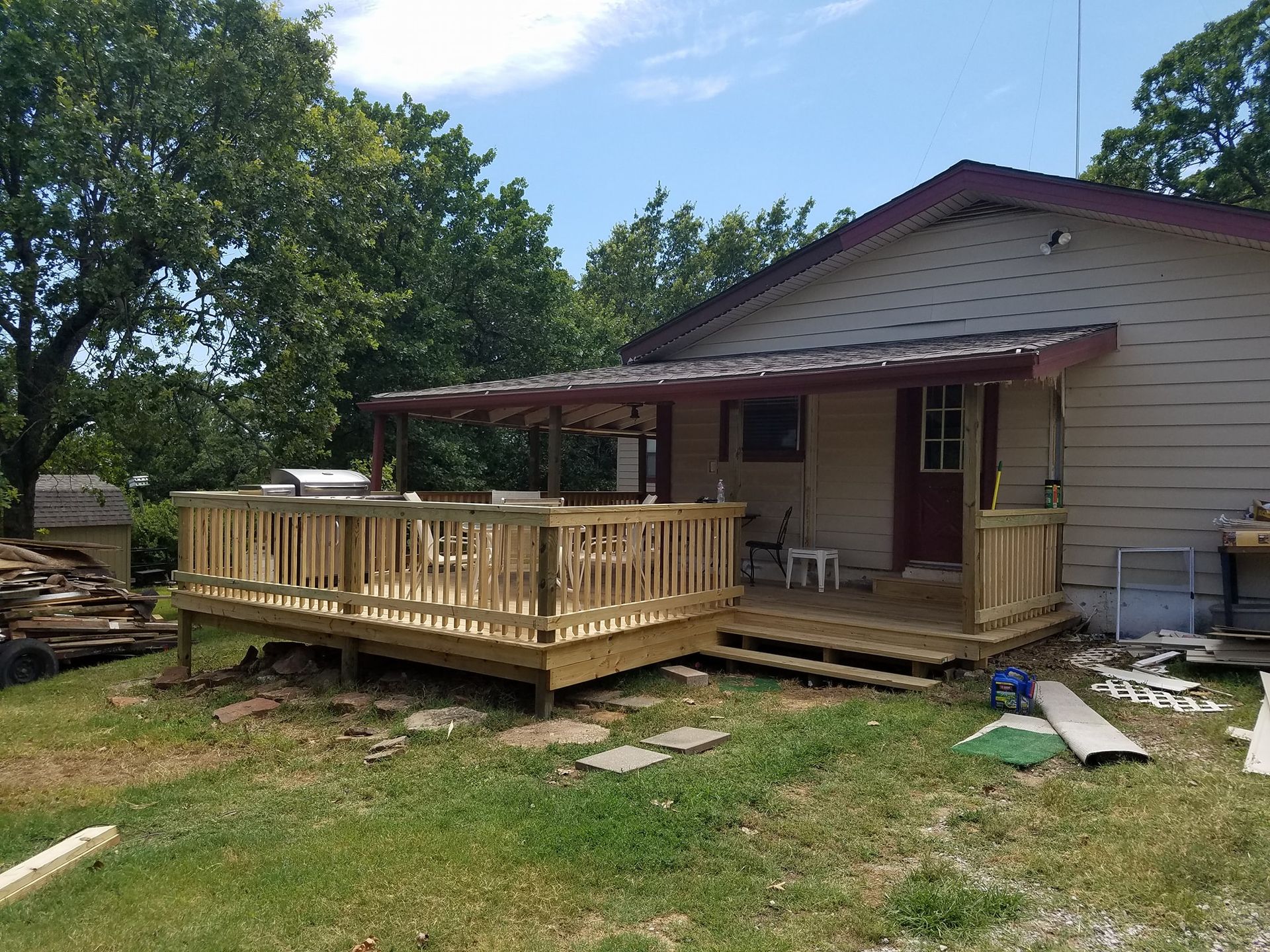 Single-story house with a newly built wooden front deck and railing in a grassy yard
