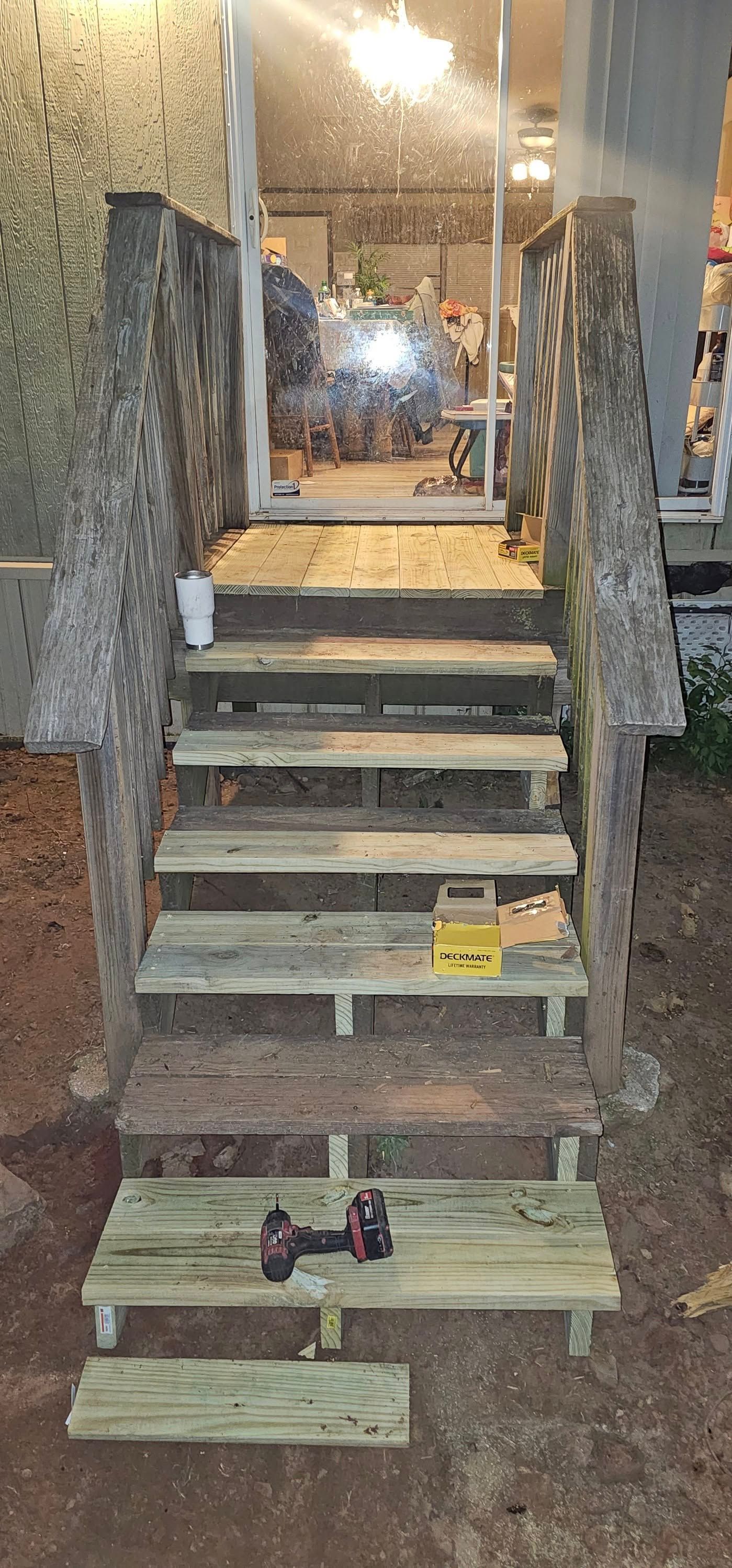 Damaged wooden steps with gaps and loose boards leading up to a house entrance at night
