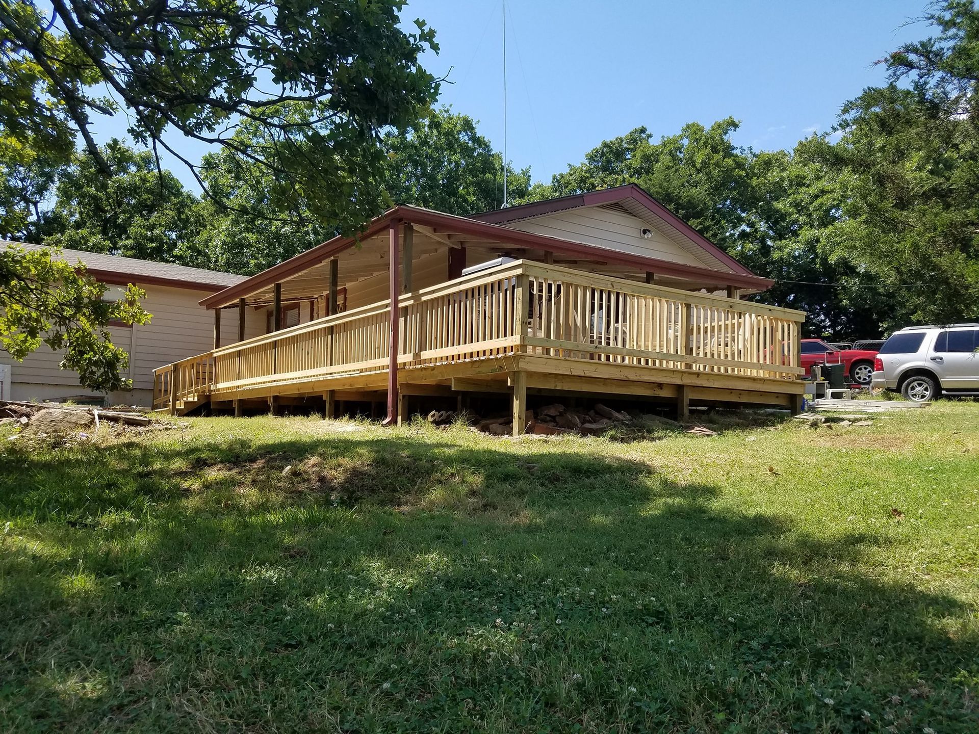 Wooden porch deck attached to a house on a grassy slope under a blue sky