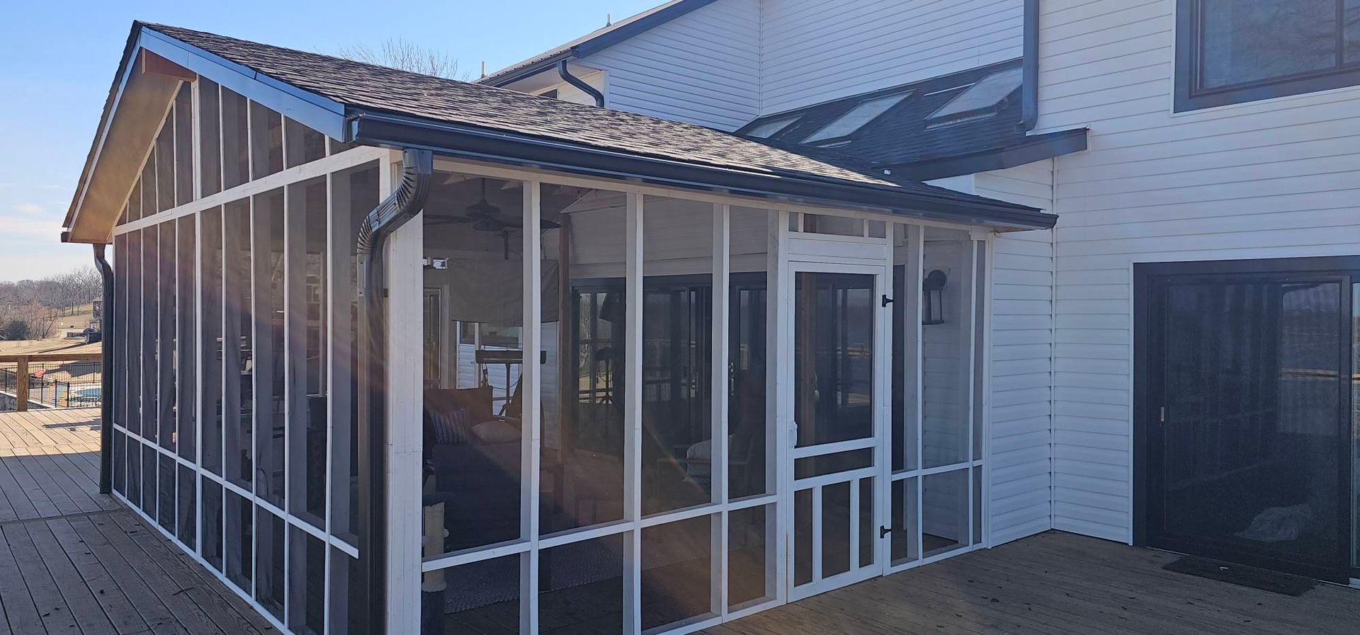 Small sunroom addition with white-framed windows and a sloped roof on a house exterior