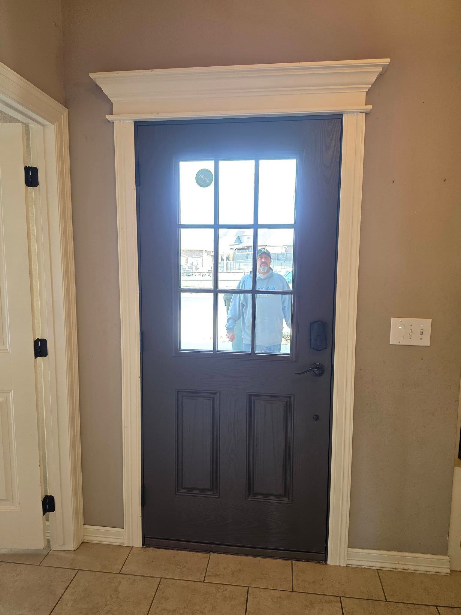 Front door with glass panes and black lower panels, showing a person outside on the porch.