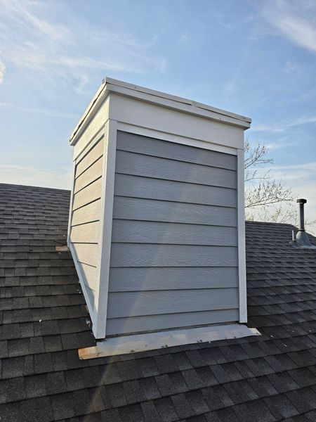 White dormer on a gray shingled roof under a blue sky
