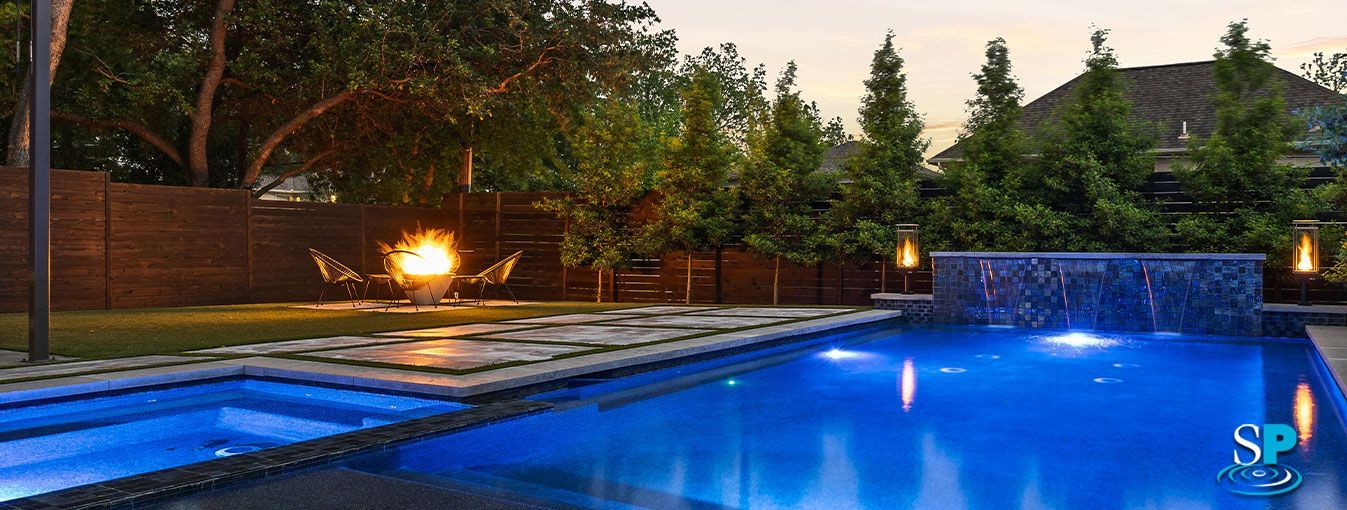 Stone outdoor pavilion with a dark wooden roof, built-in grill, and bench seating.