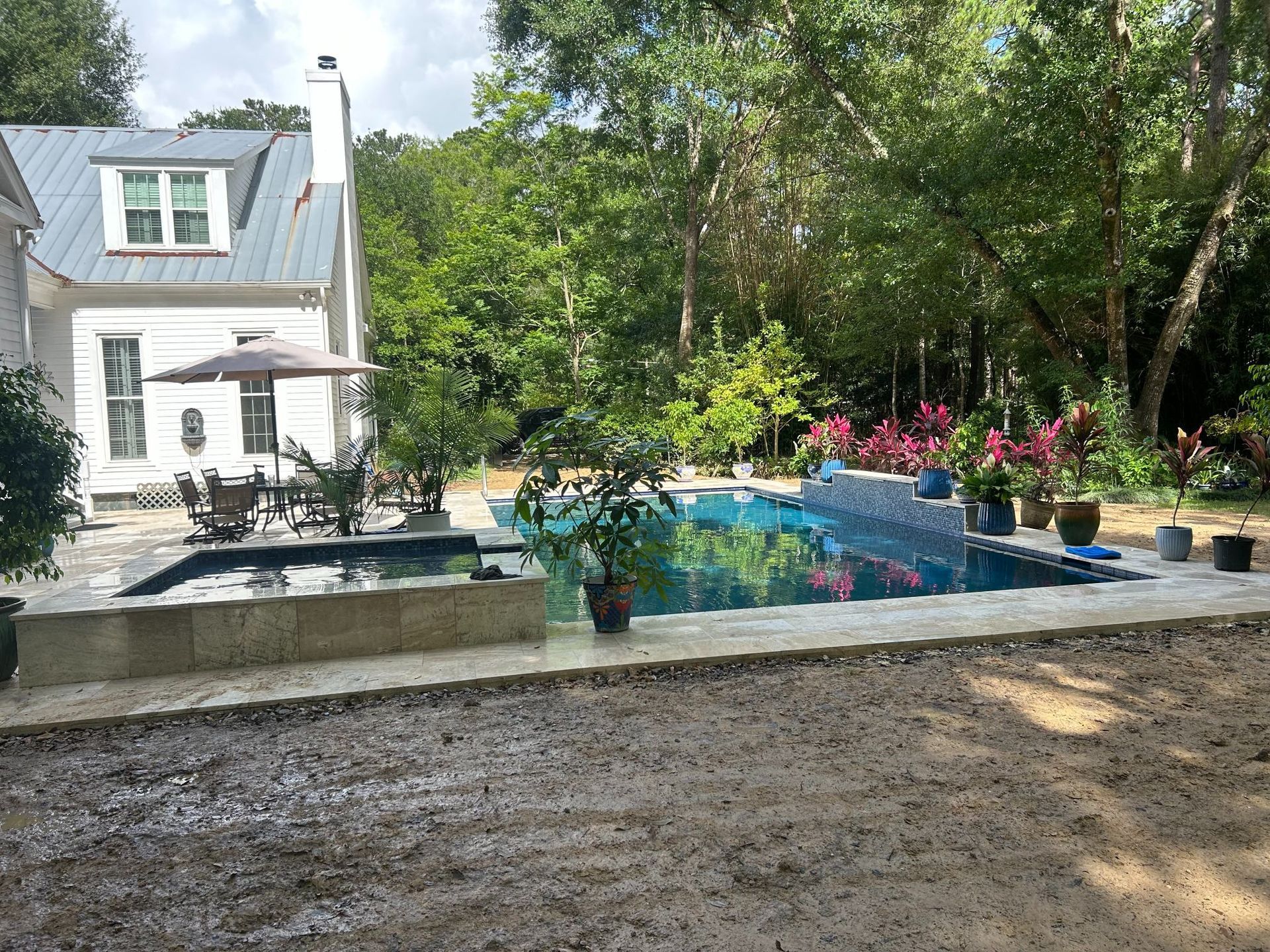 House and swimming pool in a lush backyard with trees and pink flowers