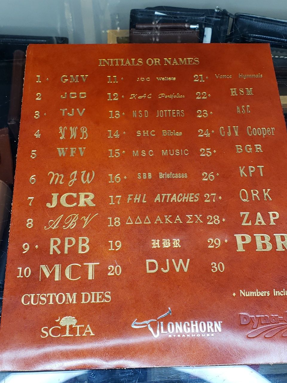 A leather panel with initials and names, numbered 1-30, in gold. 