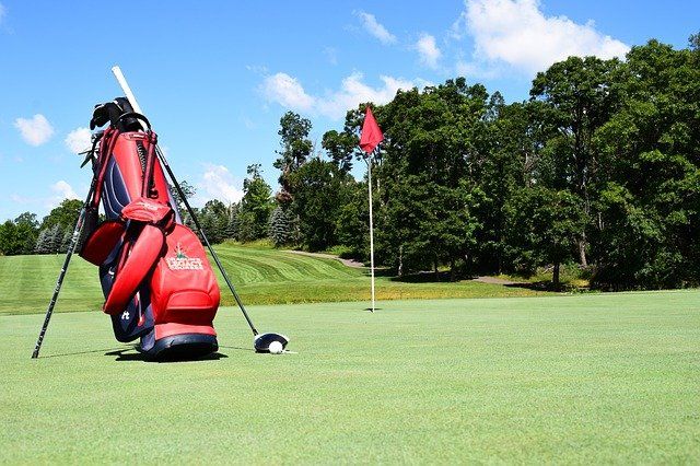 A golf bag is sitting on a golf course next to a flag.