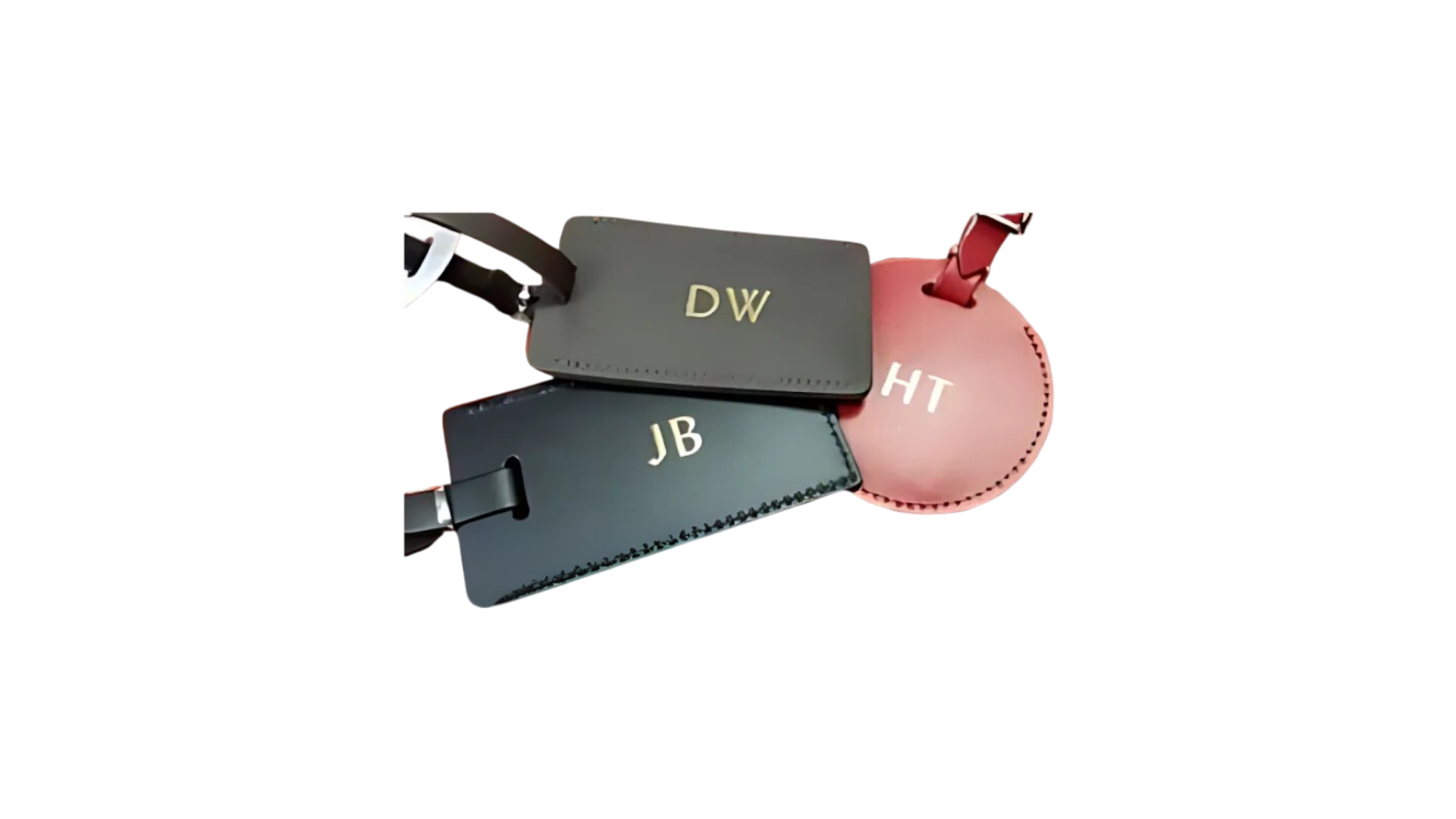 Three leather luggage tags in gray, black, and pink with initials DW, JB, and HT.