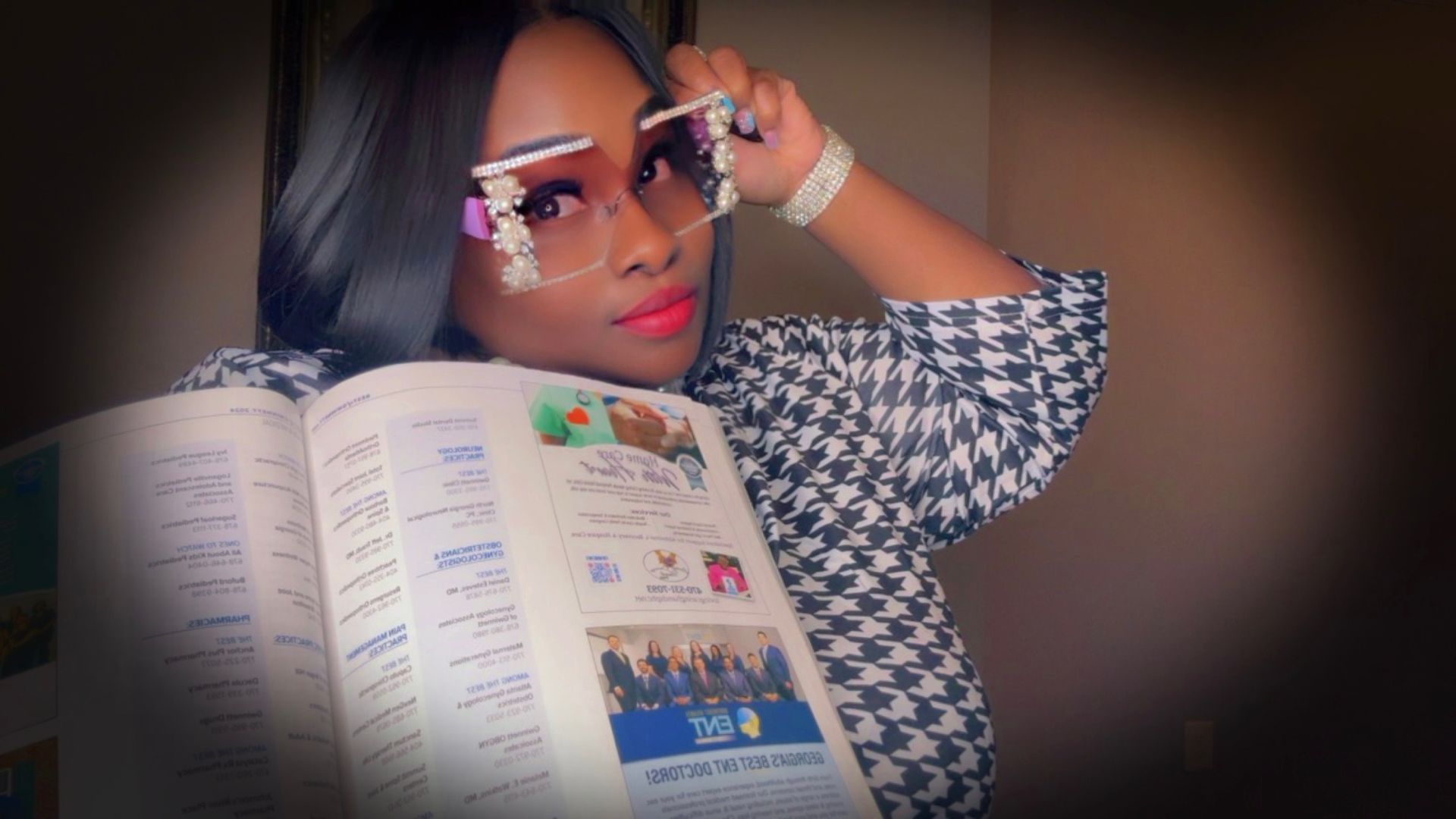 A woman wearing sunglasses is holding an open book.
