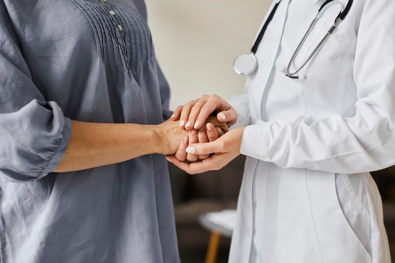 A doctor is holding a patient 's hand in a hospital.