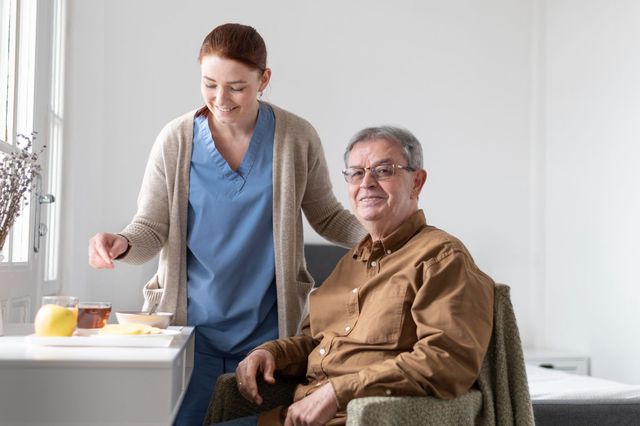 A woman is feeding an elderly man in a wheelchair.