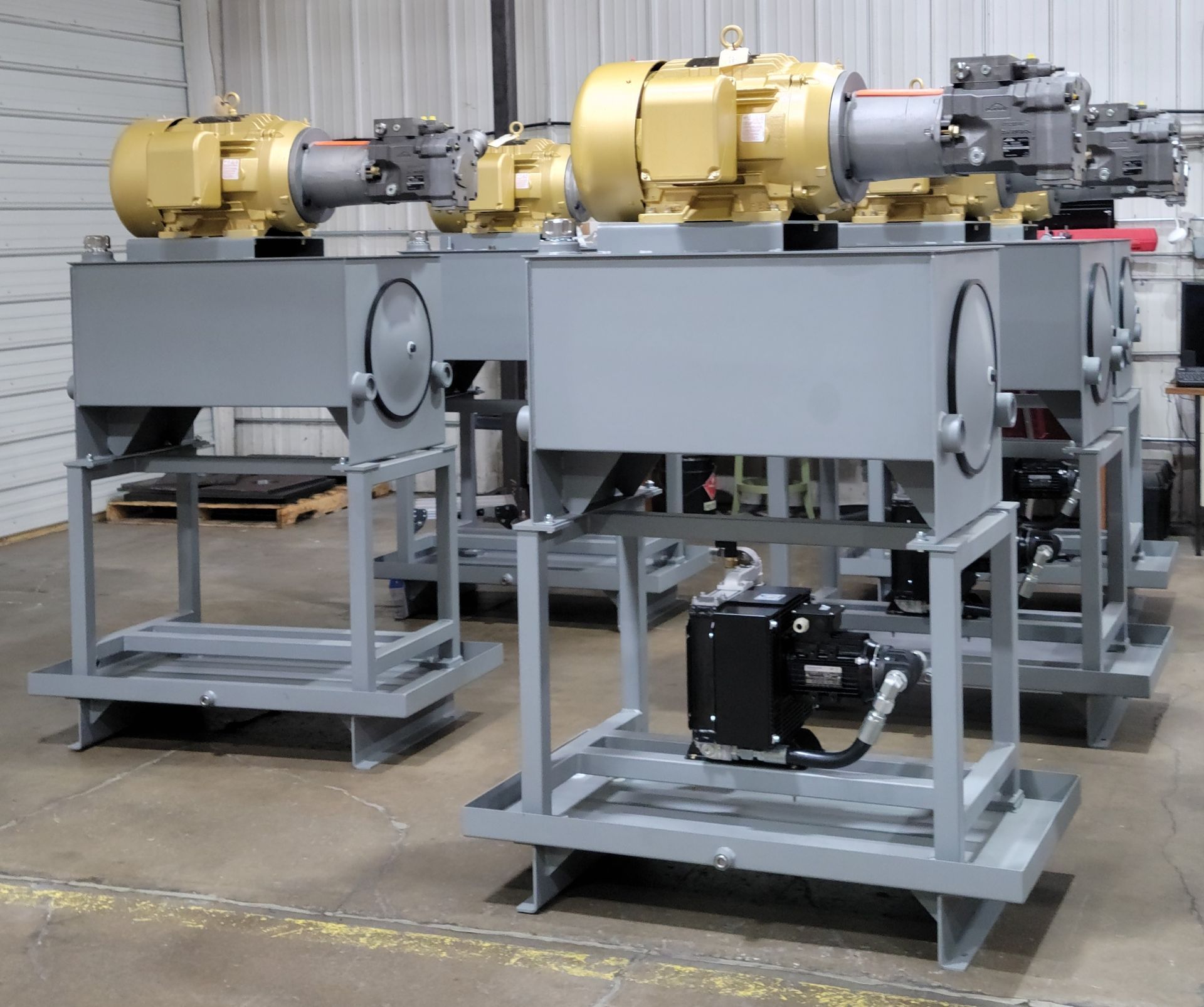 Several gray industrial machines with beige motors, in a factory setting.
