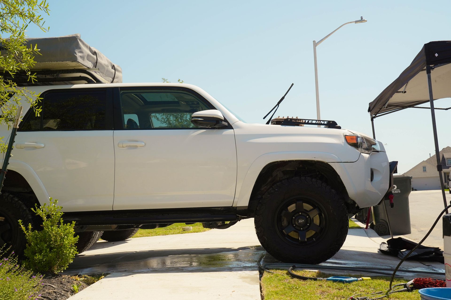 A white suv is parked on the side of the road next to a tent.