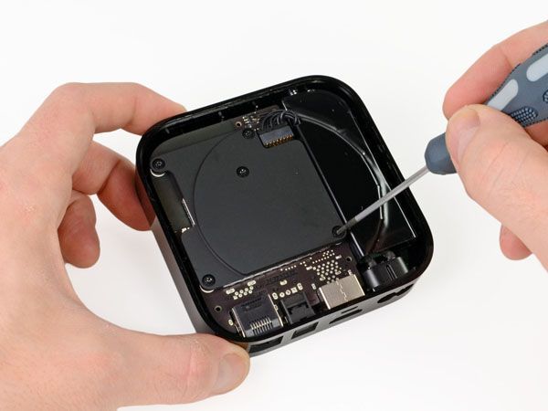 A person is holding a small black box with a screwdriver