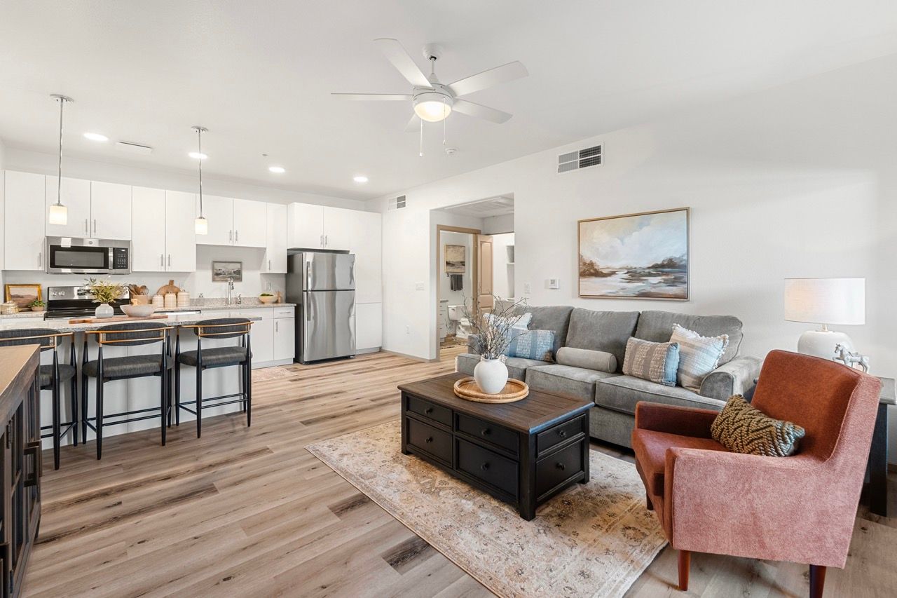 Open-concept living room and kitchen with white cabinets, stainless appliances, and an island.