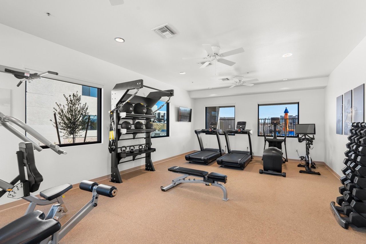 Interior view of a modern residents' gym with treadmills, free weights, and benches.