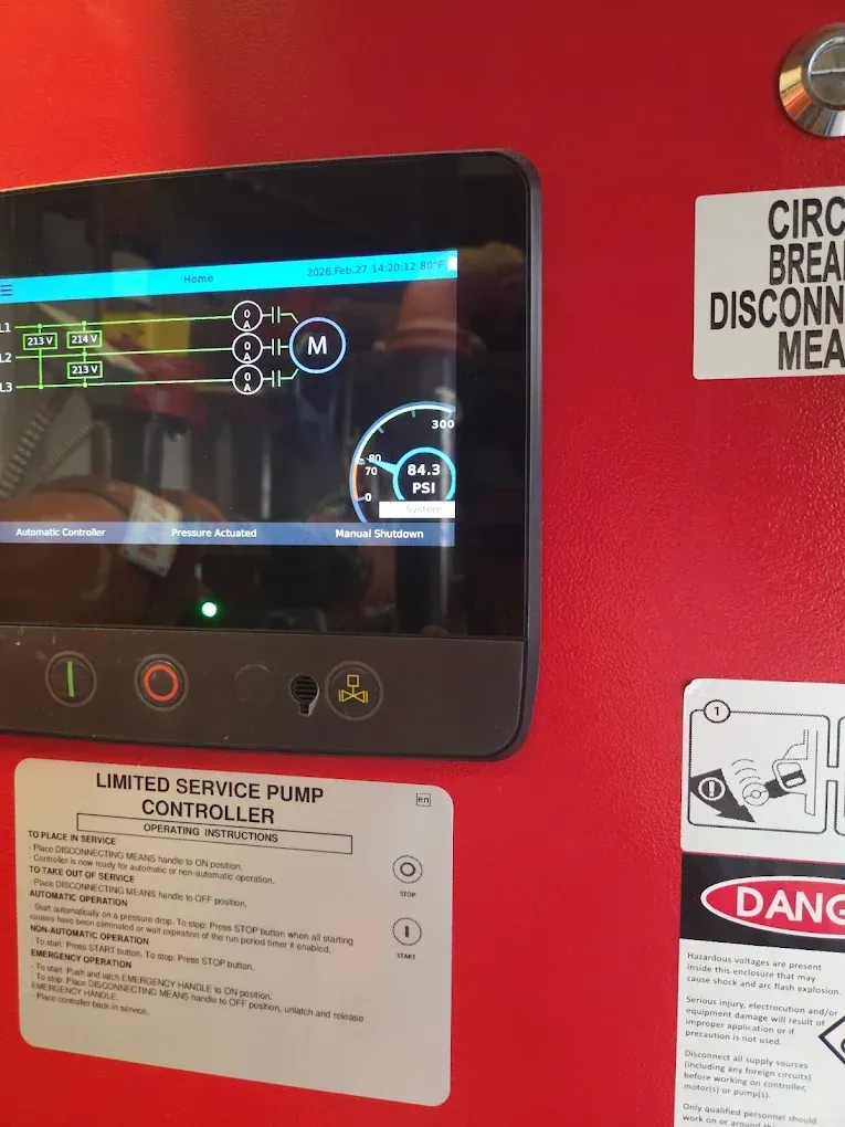 Red emergency equipment panel with a small screen, buttons, and warning labels on a wall.