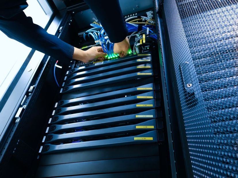 Hands connecting cables inside a blue-lit server rack