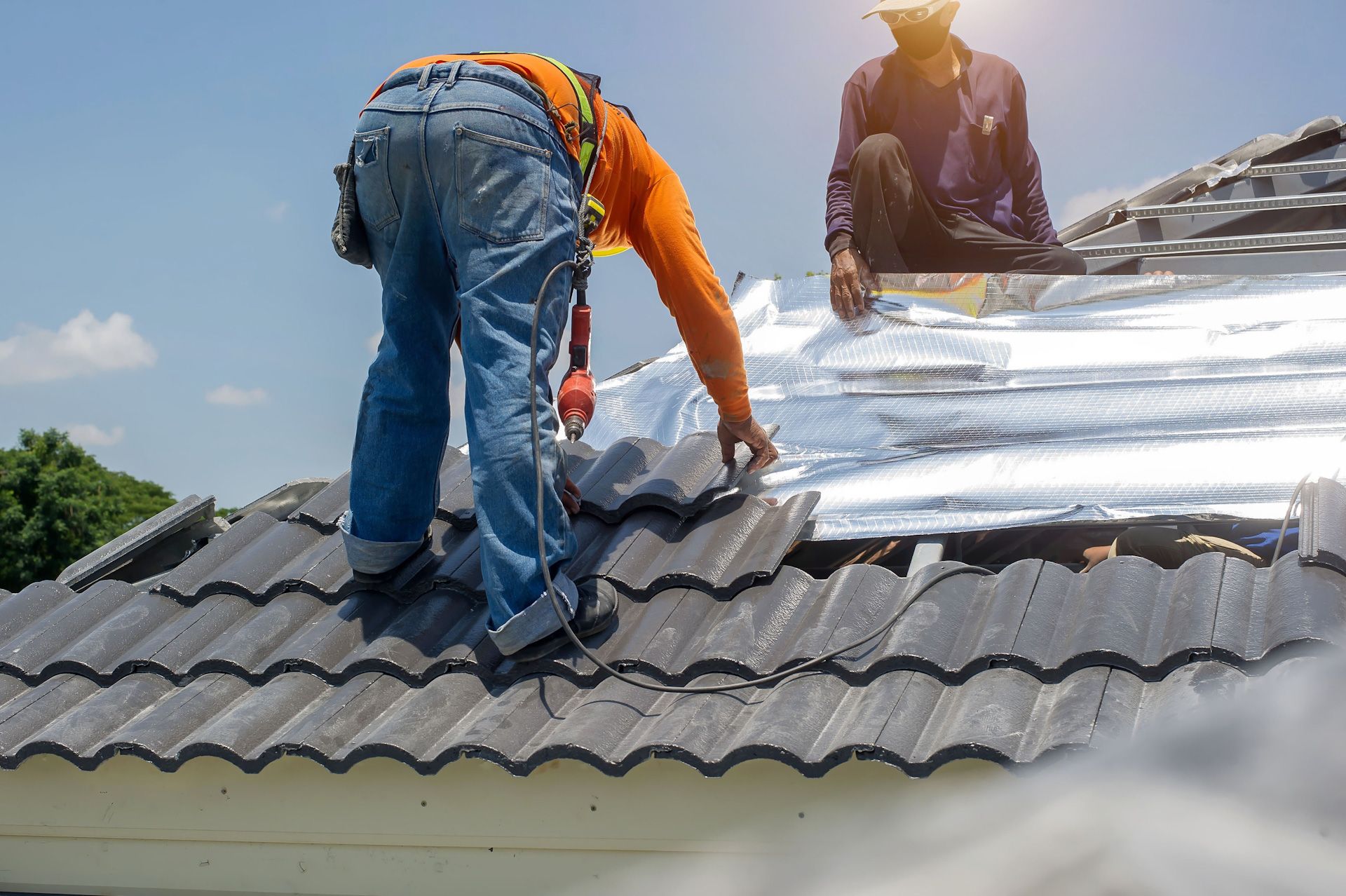 Two men are working on the roof of a house.