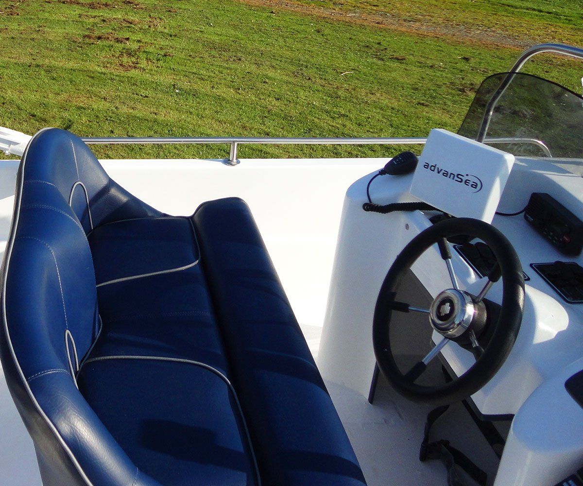 Blue and white boat interior with steering wheel and seat.