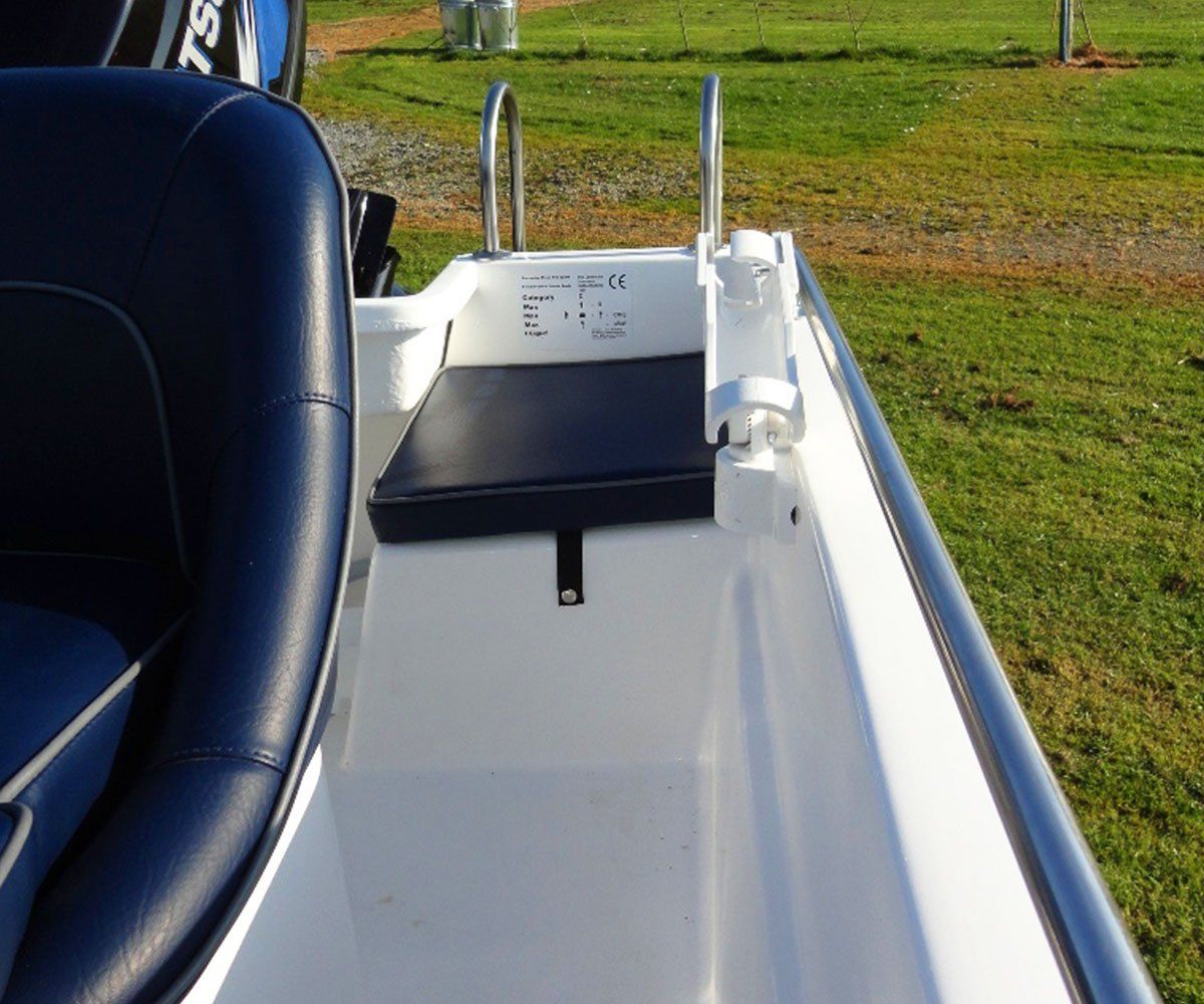 White boat interior with navy blue seat and ladder, sitting on grass.