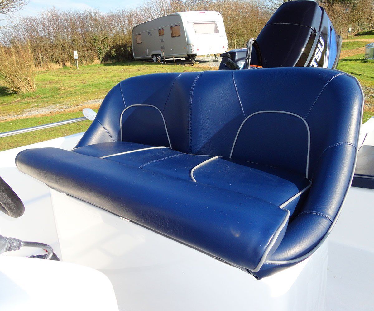 Blue boat seat with white trim, a blue motor, and a trailer in the background.