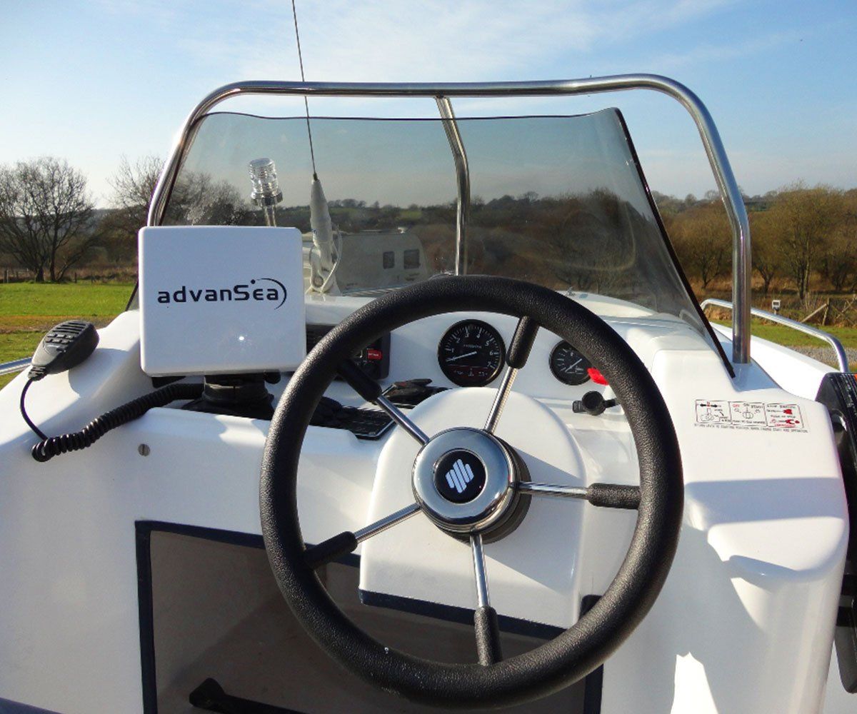 Boat cockpit with steering wheel, instruments, navigation screen, and windshield.