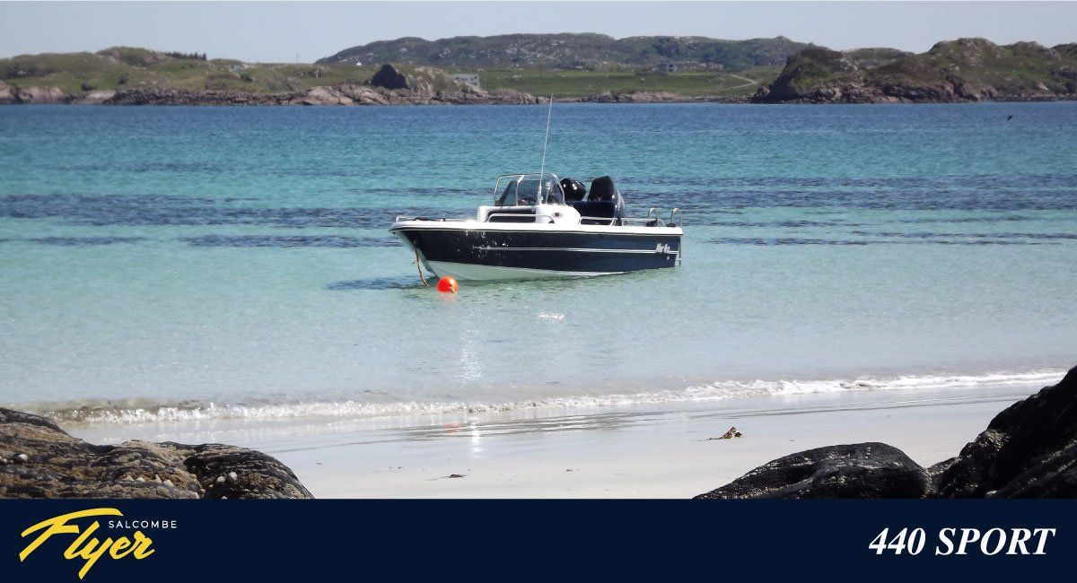 Boat at anchor in clear turquoise water near a beach, coastal background.