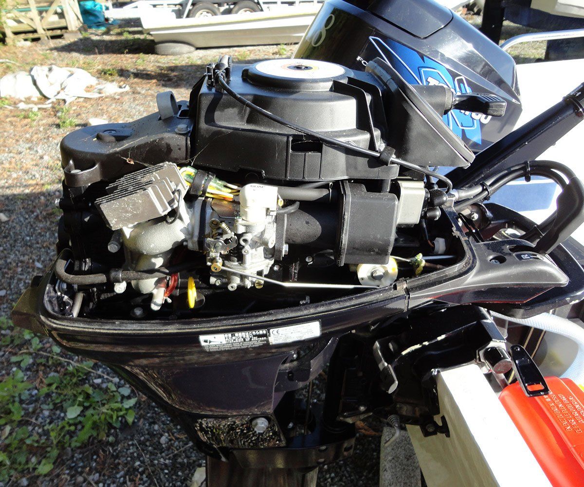 Black outboard boat motor with exposed engine components; outdoors.