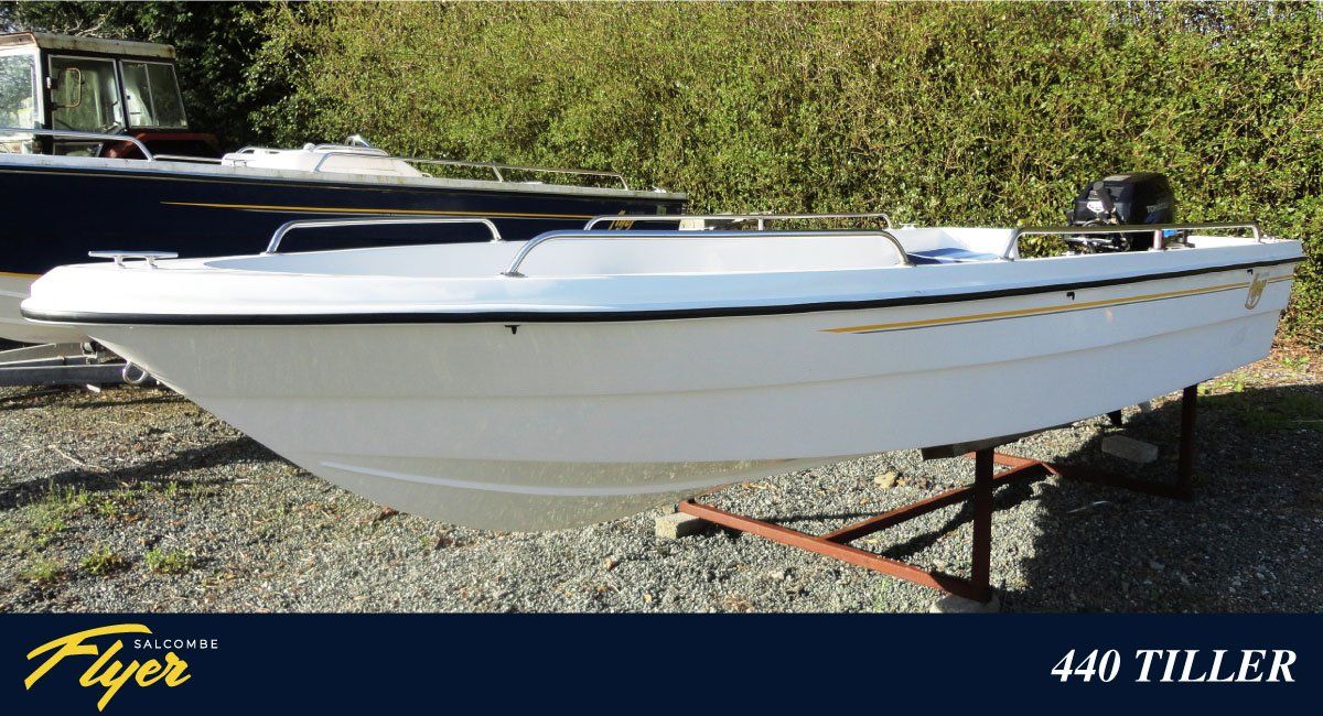 White boat with outboard motor, on a stand outdoors, labeled
