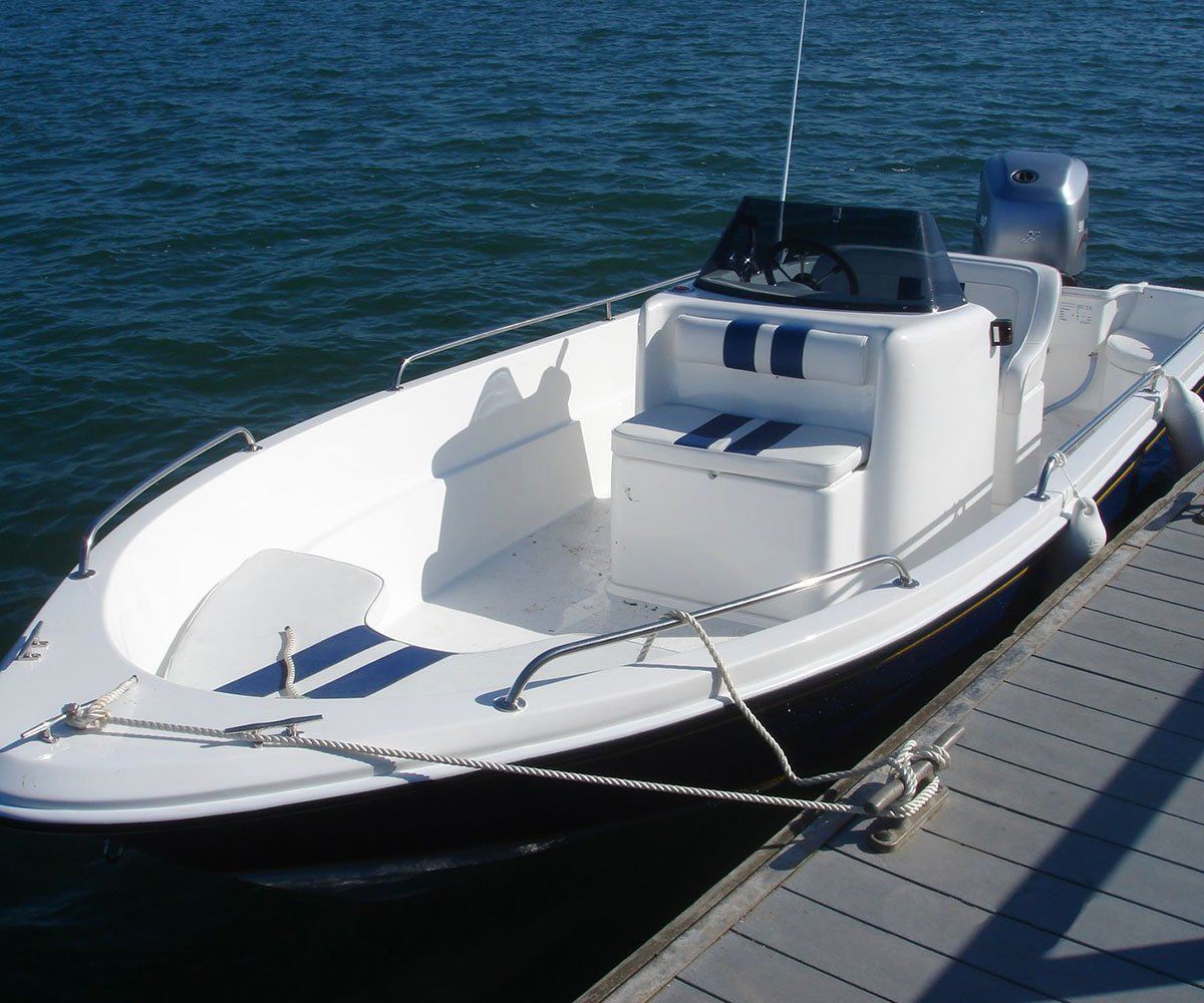 White motorboat tied to a dock, blue stripes on seating, gray outboard motor, on the water.