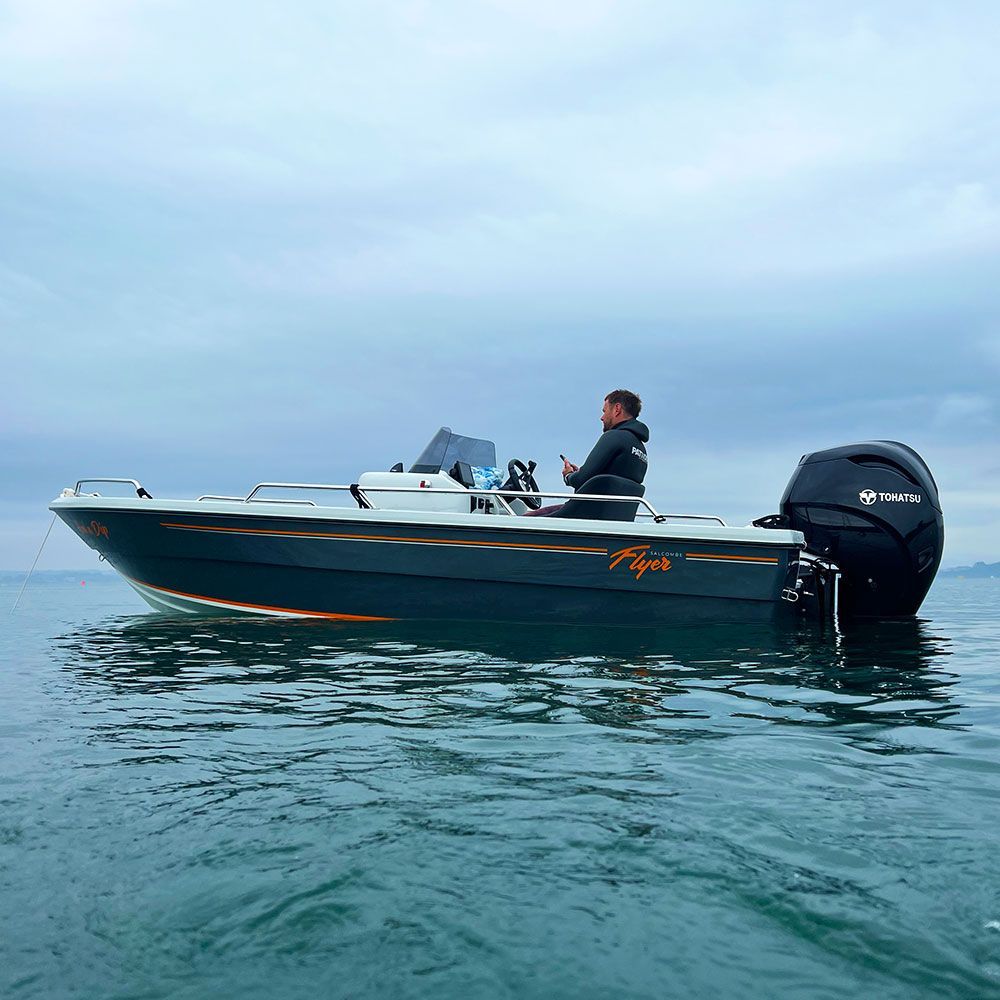 A man on a motorboat in a body of water under a cloudy sky.