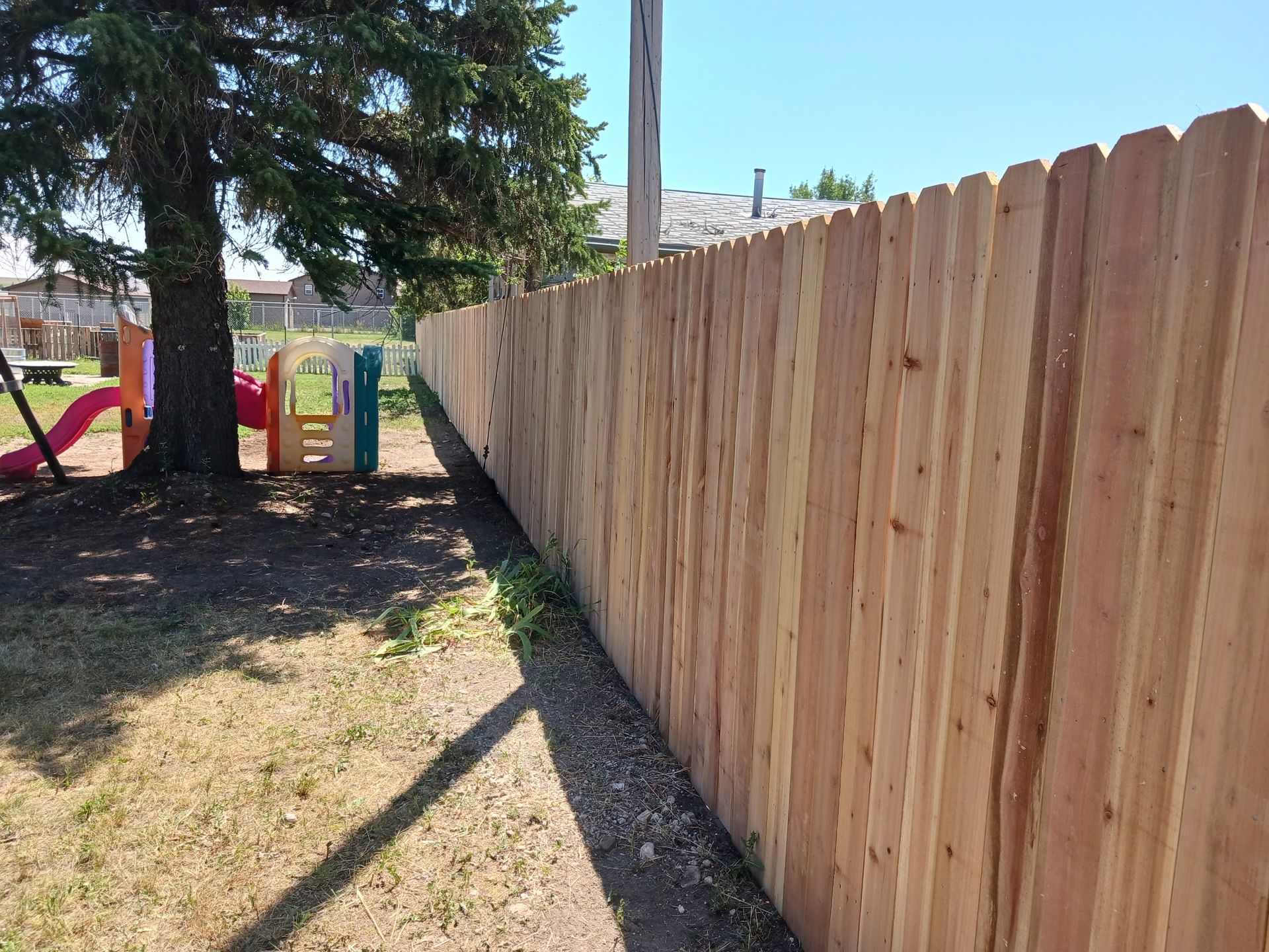 A wooden fence with a playground in the background