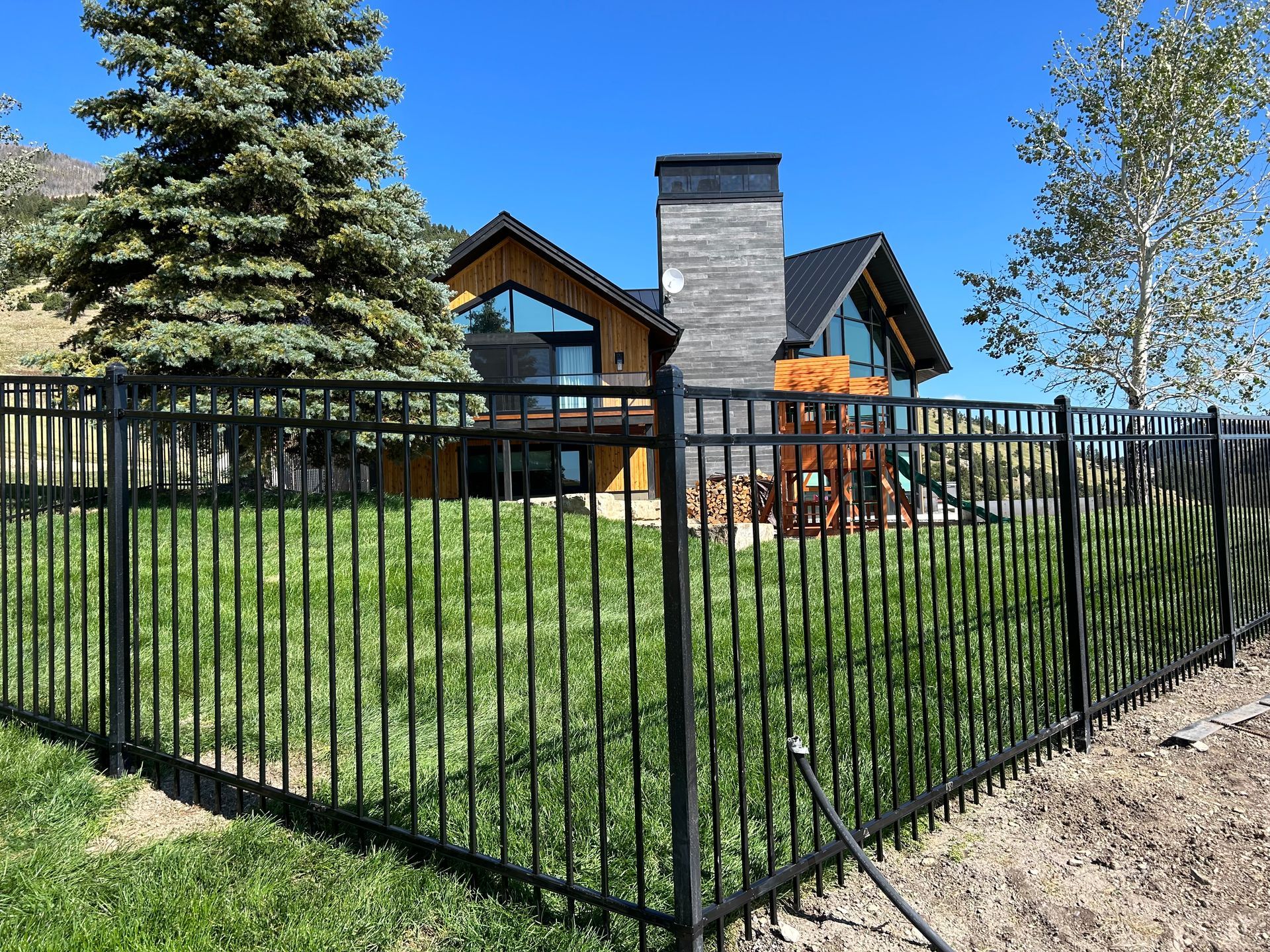 A large house is behind a black fence.
