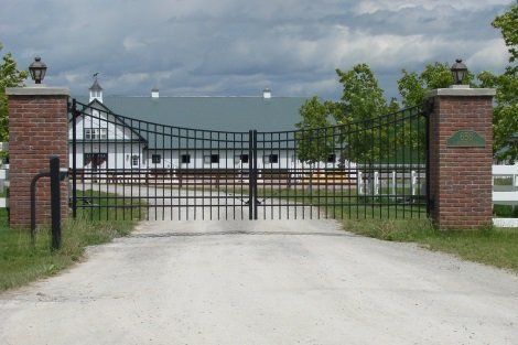 A gate leading to a farm with a white building in the background